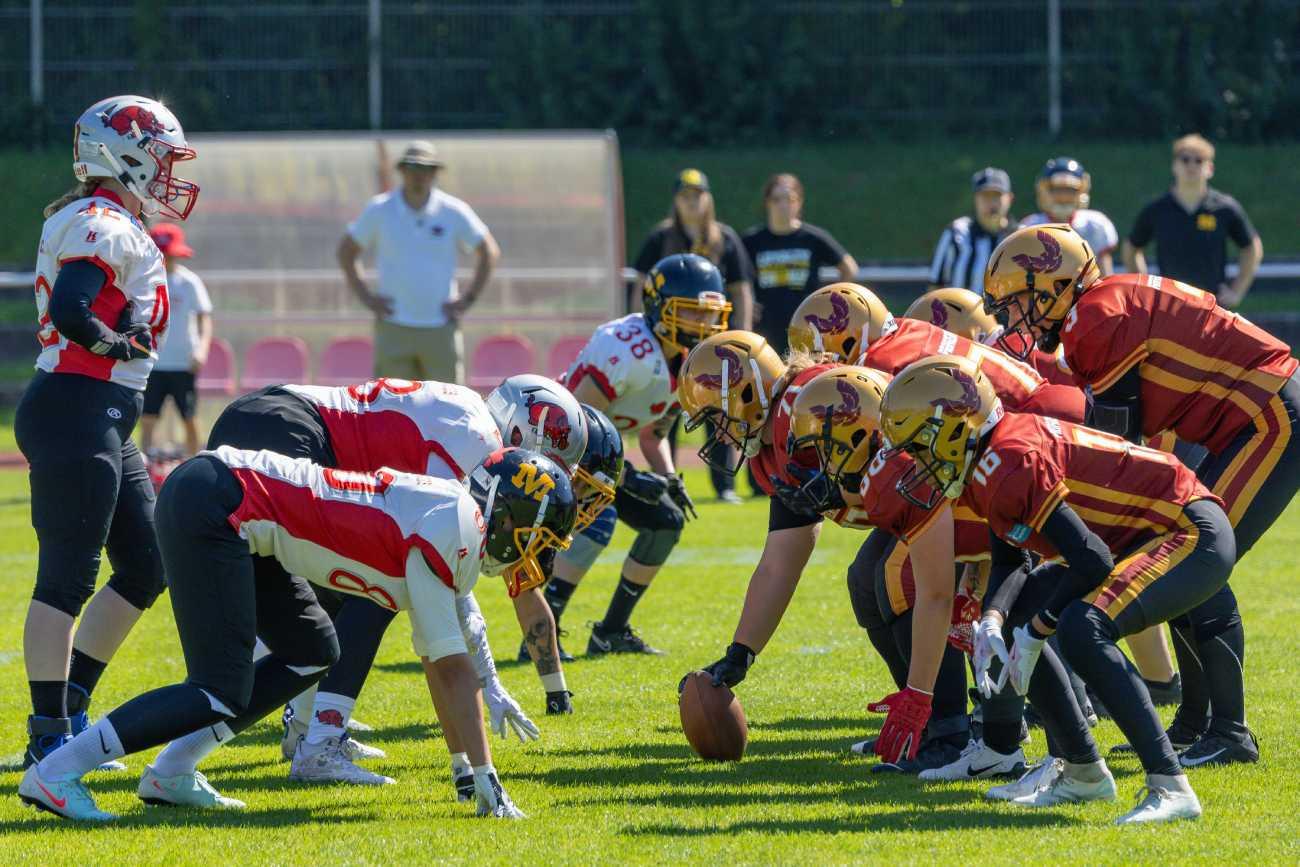 Zwei Frauenteams des American Football stehen sich auf dem Spielfeld gegenüber.
