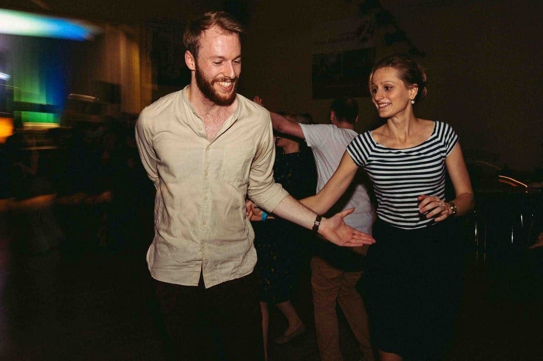 Ein junger Mann und eine junge Frau beim ausgelassenen Lindy-Hop Paartanz bei Swingmaniacs in Regensburg. Beide lachen.