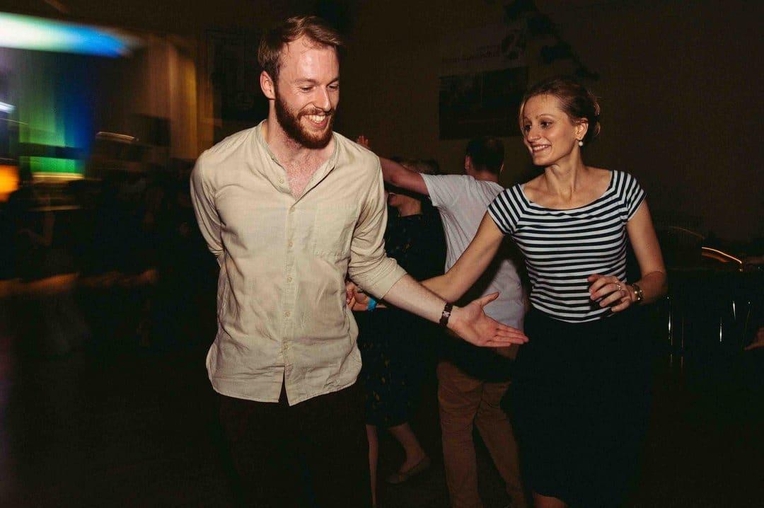 Ein junger Mann und eine junge Frau beim ausgelassenen Lindy-Hop Paartanz bei Swingmaniacs in Regensburg. Beide lachen.