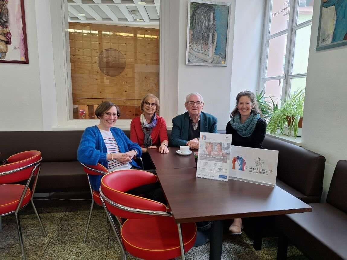 Eine Gruppe Männer und Frauen sitzen zusammen beim Kaffeetreff.