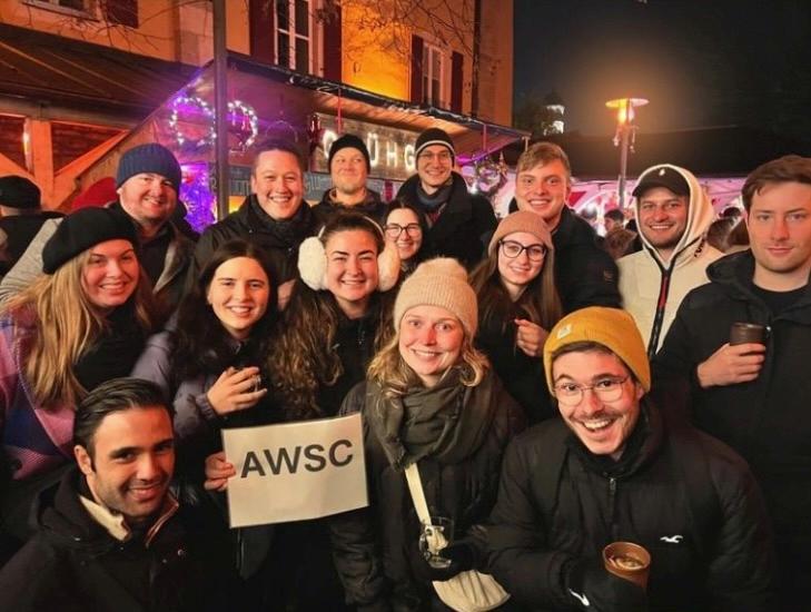 Eine große Gruppe junger Menschen feiert abends in der Stadt.
