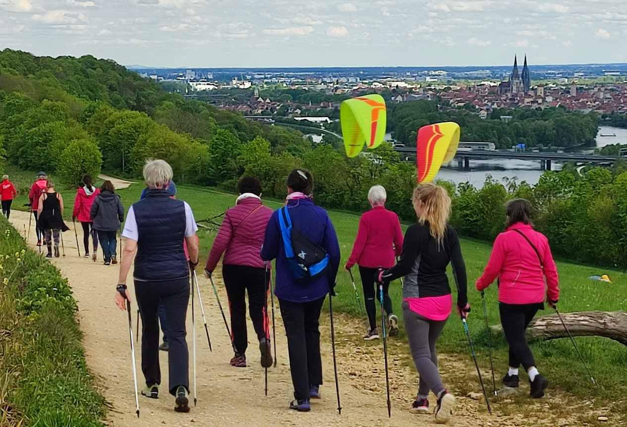 Eine Nordic Walkinggruppe wandert auf einem Feldweg bei Regensburg.