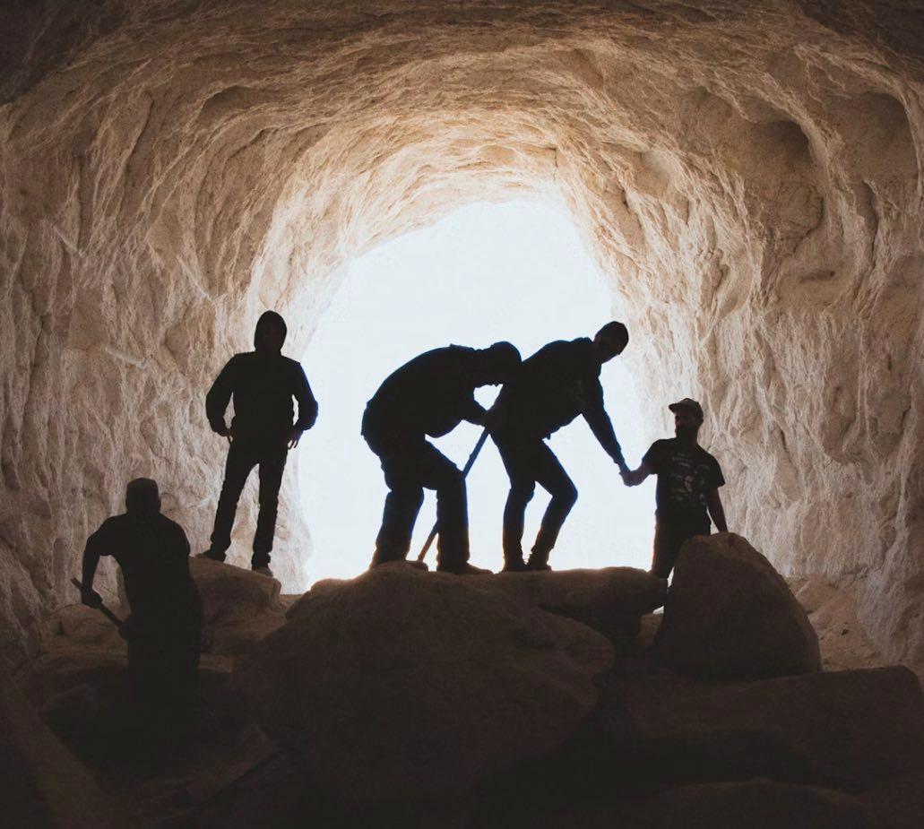 Ein Eingang zu einer Höhle mit einer Gruppe an Entdeckern im Gegenlicht fotografiert. Stellvertretend für die Höhlenforschung Oberpfalz