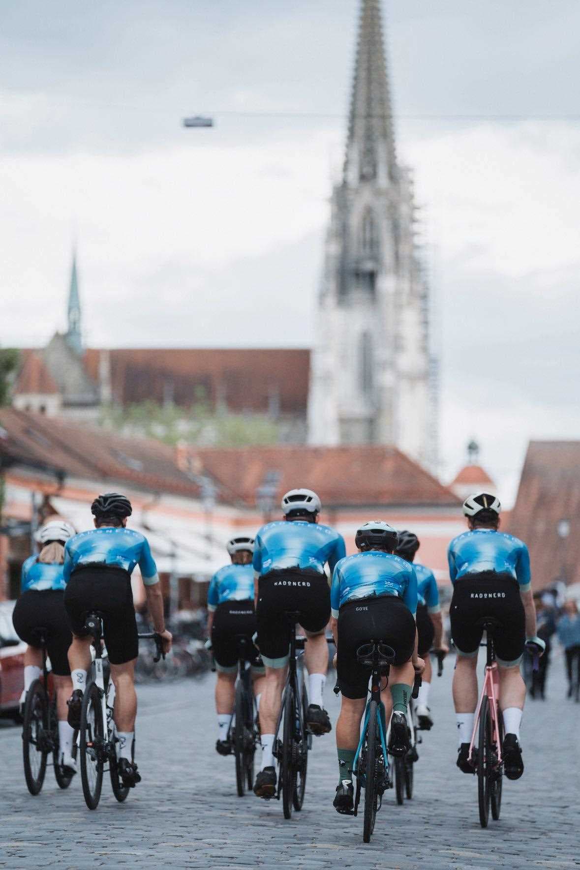 Eine Gruppe von Radfahrern radelt über die Steinerne Brücke vor dem Dom.
