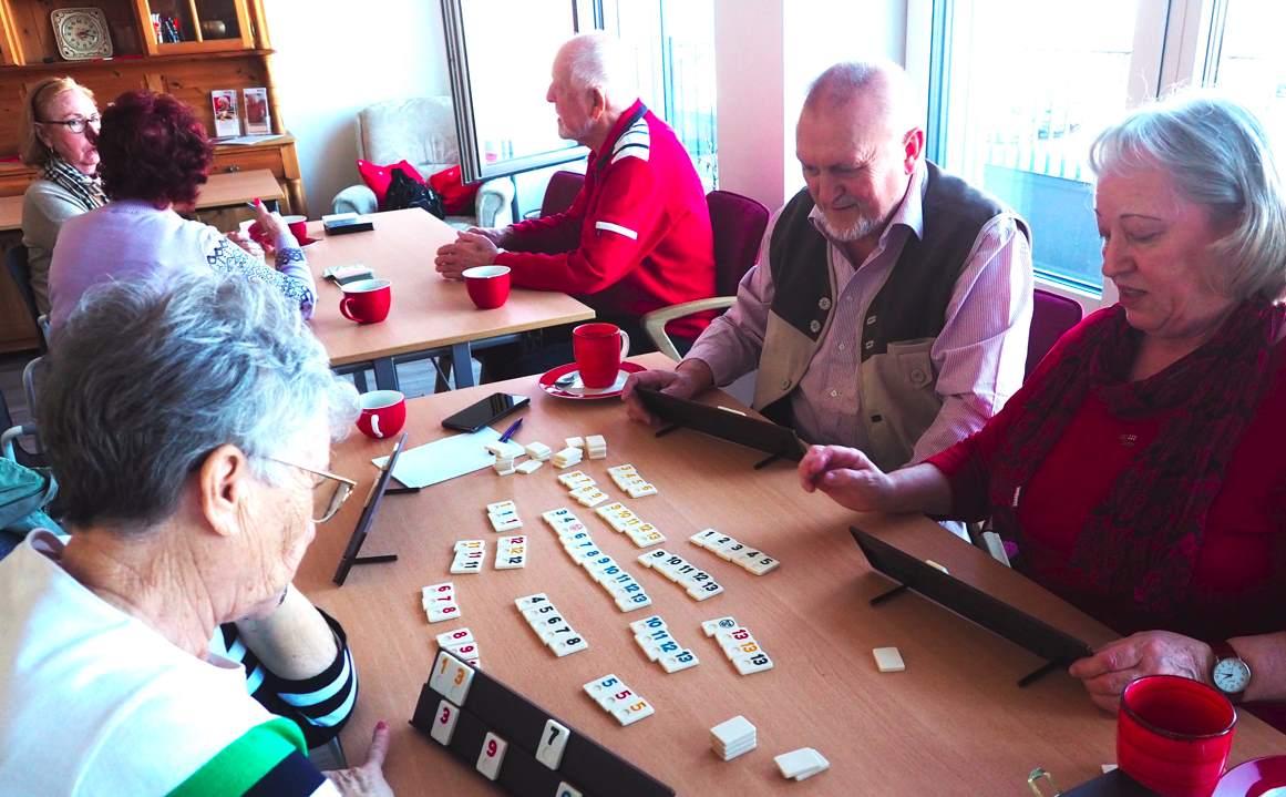 Senioren sitzen beisammen und Spielen Brett- und Kartenspiele.