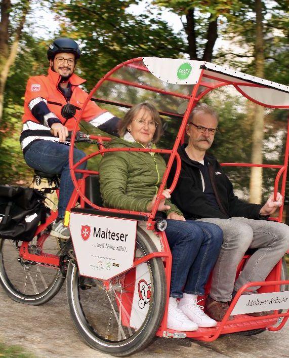 Senioren werden in einer Elektrorikscha durch den Park gefahren.