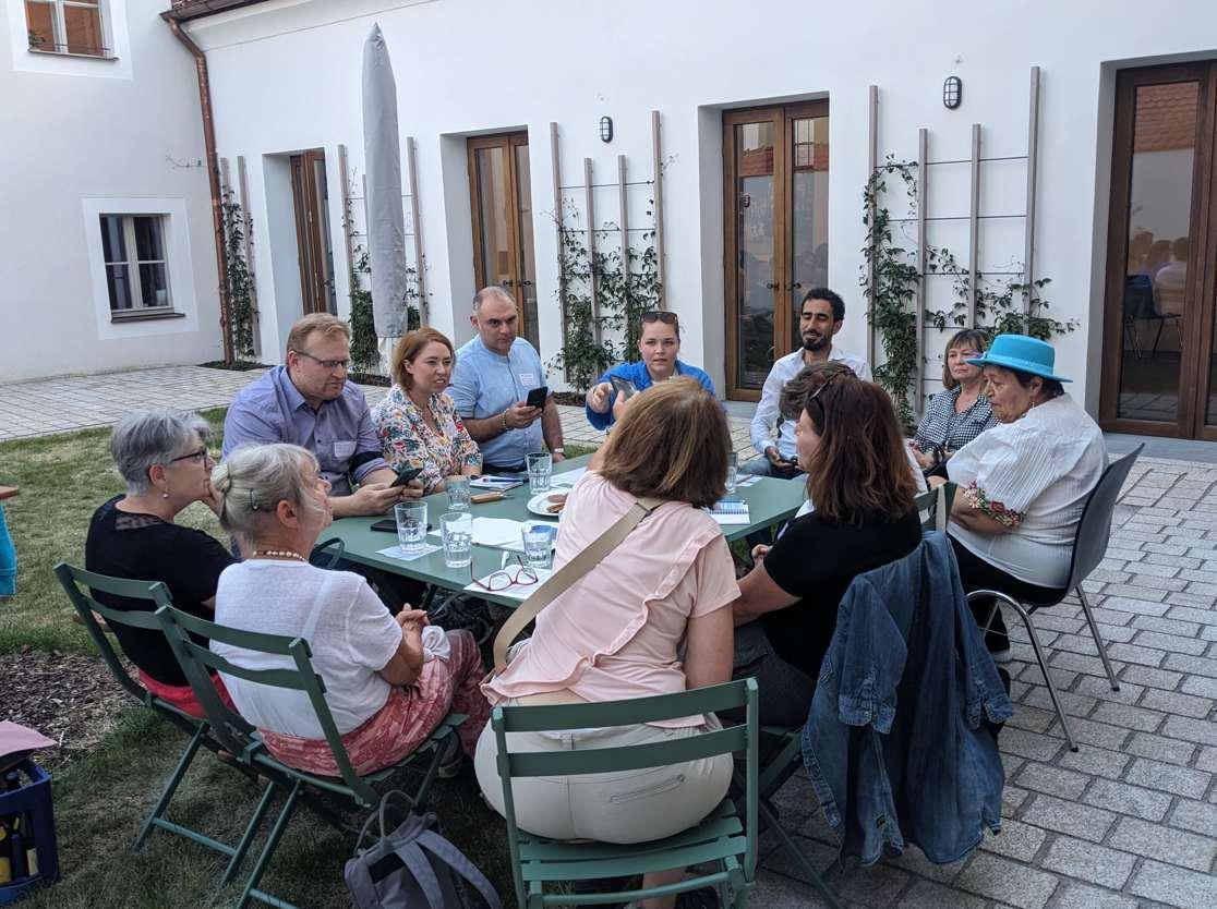 Menschen sitzen zusammen im Garten an einem Kaffeetisch.
